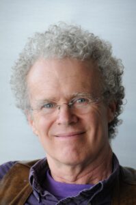 Erik Olin Wright smiling, curling grey-white hair and clear framed glasses.